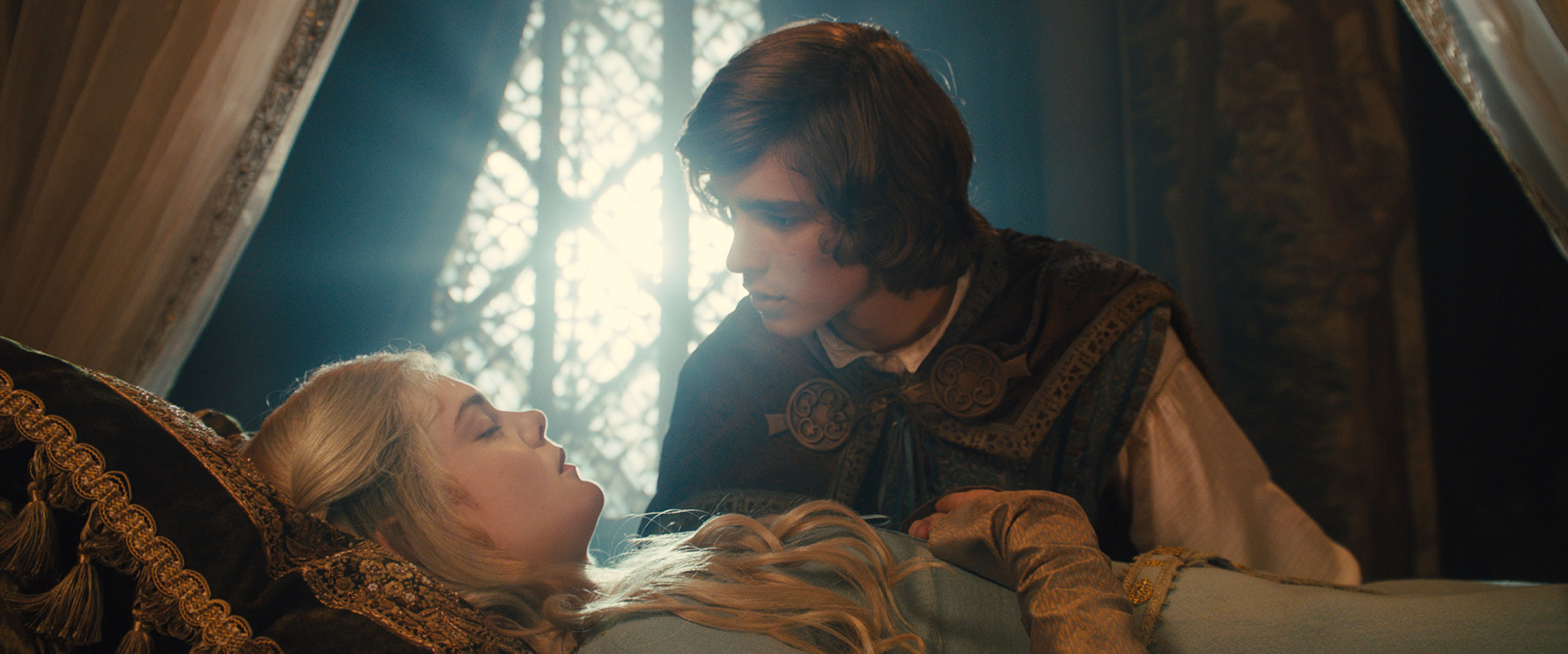 Aurora (Elle Fanning) in a cursed sleep, Prince Phillip leaning over her. From Maleficent.