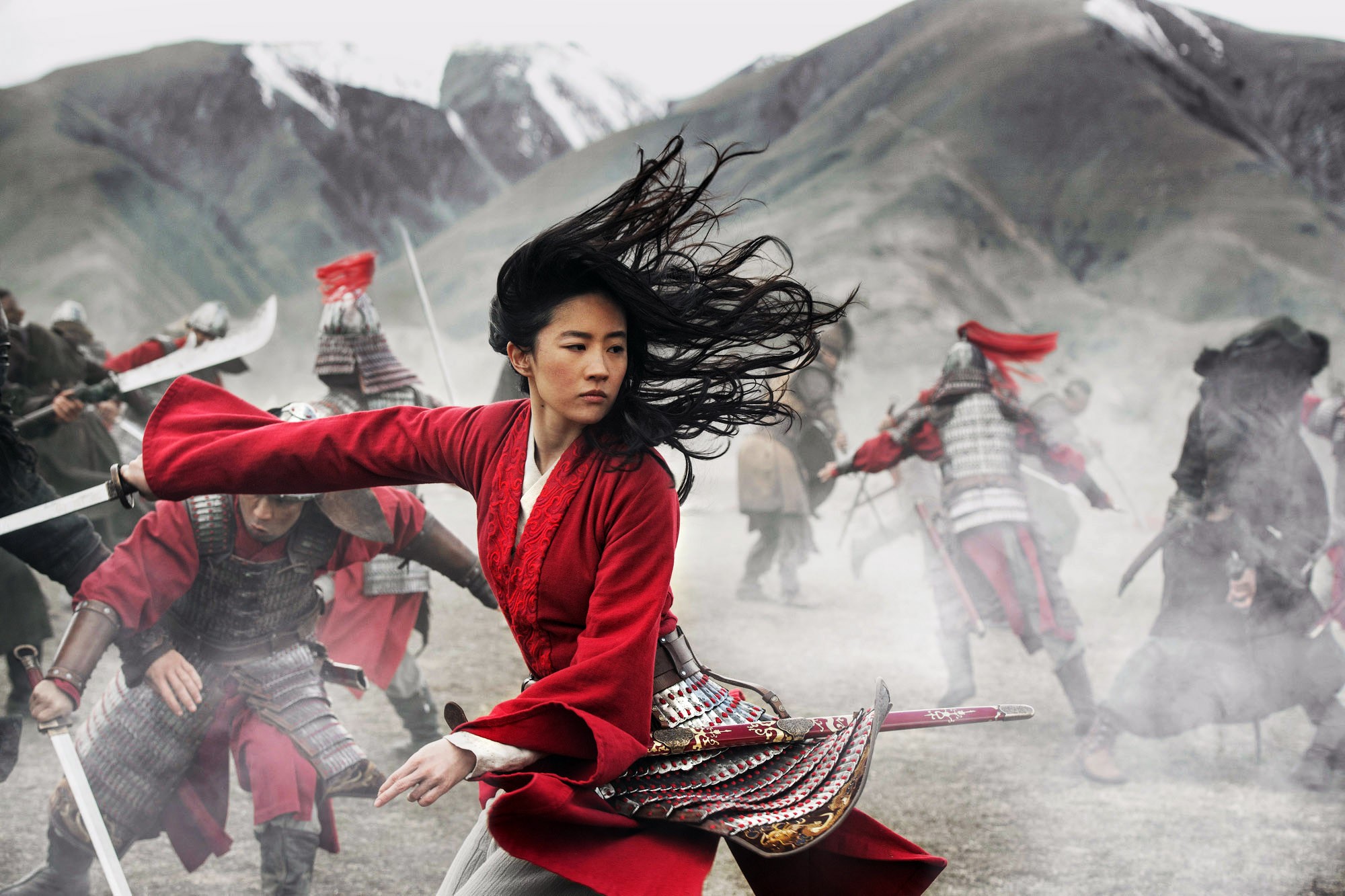 Mulan (Liu Yifei) on a chaotic battlefield in a long-sleeved red outfit, hair flying in the wind, in the live-action Mulan