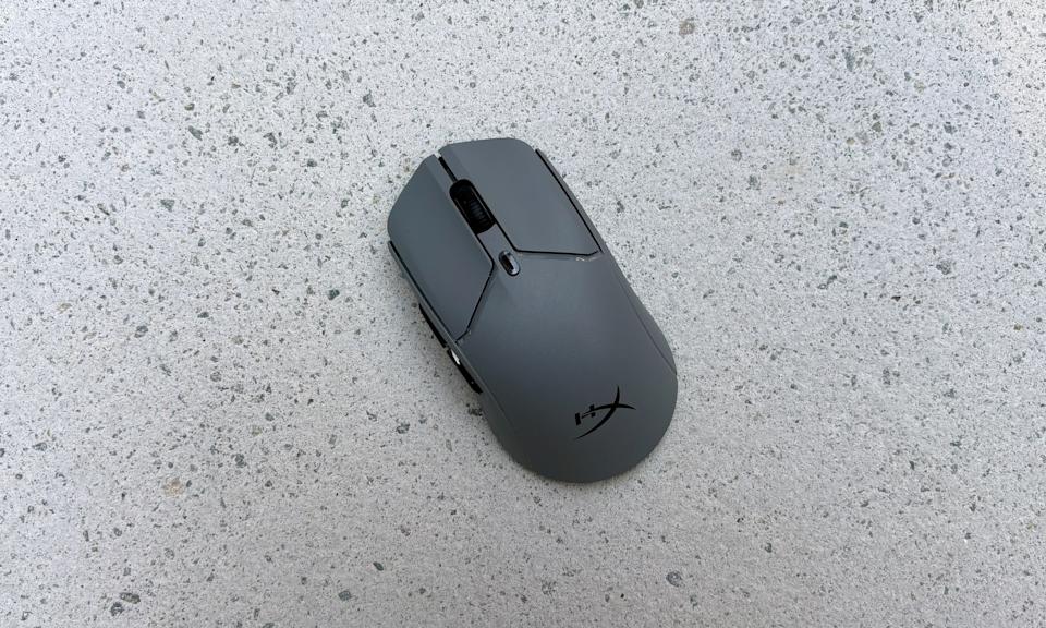 A gray gaming mouse rests on a light granite tile.