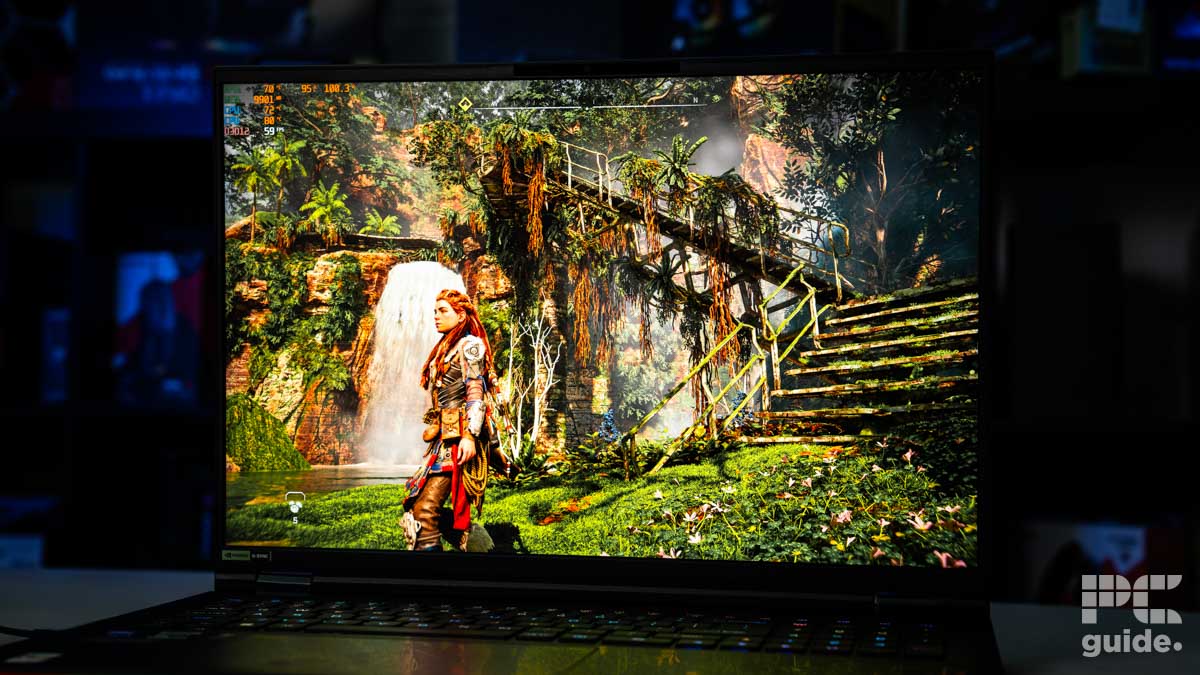 A screenshot from Horizon Forbidden West with an overgrown metal staircase and the main character on the left side. Sitting on a white table with a blurred background of shelves filled with boxed of tech products.