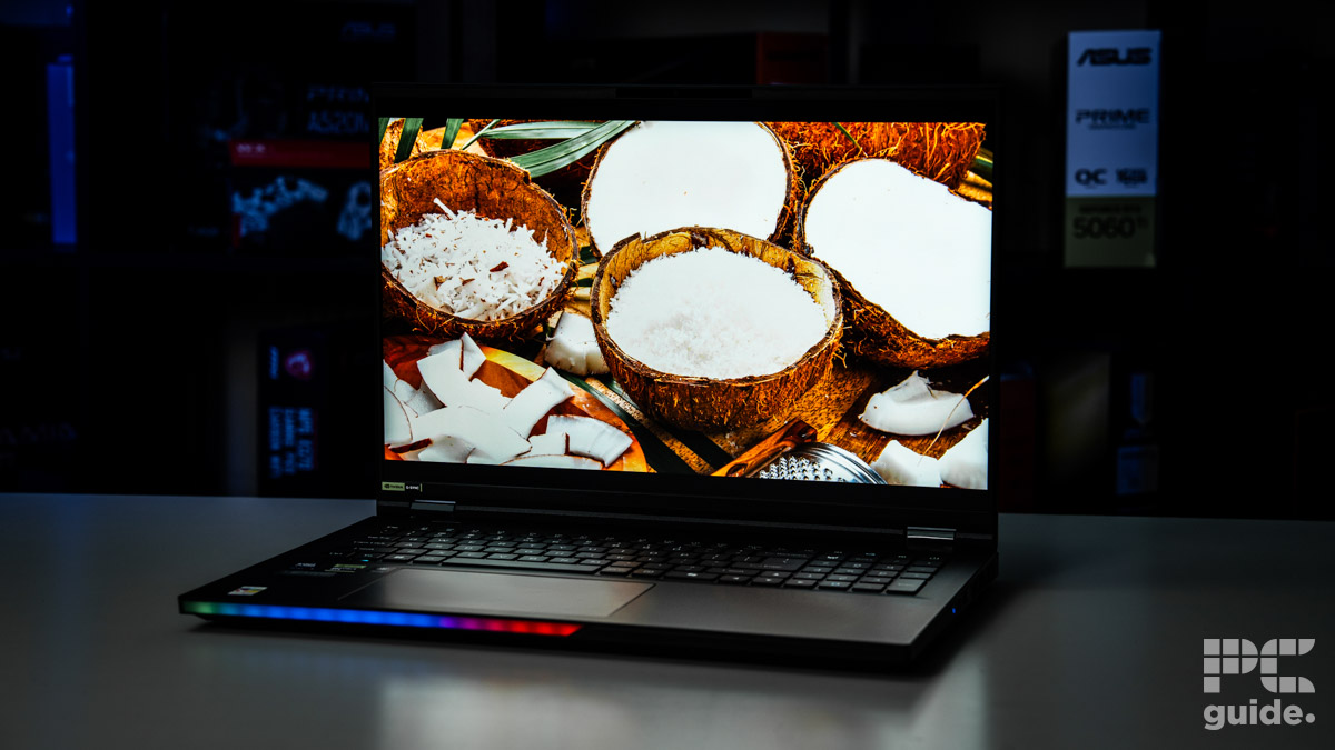 A close up of the display on the laptop that is showing off a bunch of coconuts filled with desicated coconuts. Sitting on a white table with a blurred background of shelves filled with boxed of tech products.