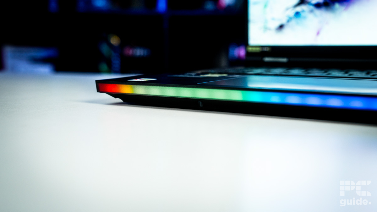 A close up of the bottom edge RGB bar. It is a range of colors of red, orange, green, to blue. Sitting on a white table with a blurred background of shelves filled with boxed of tech products.
