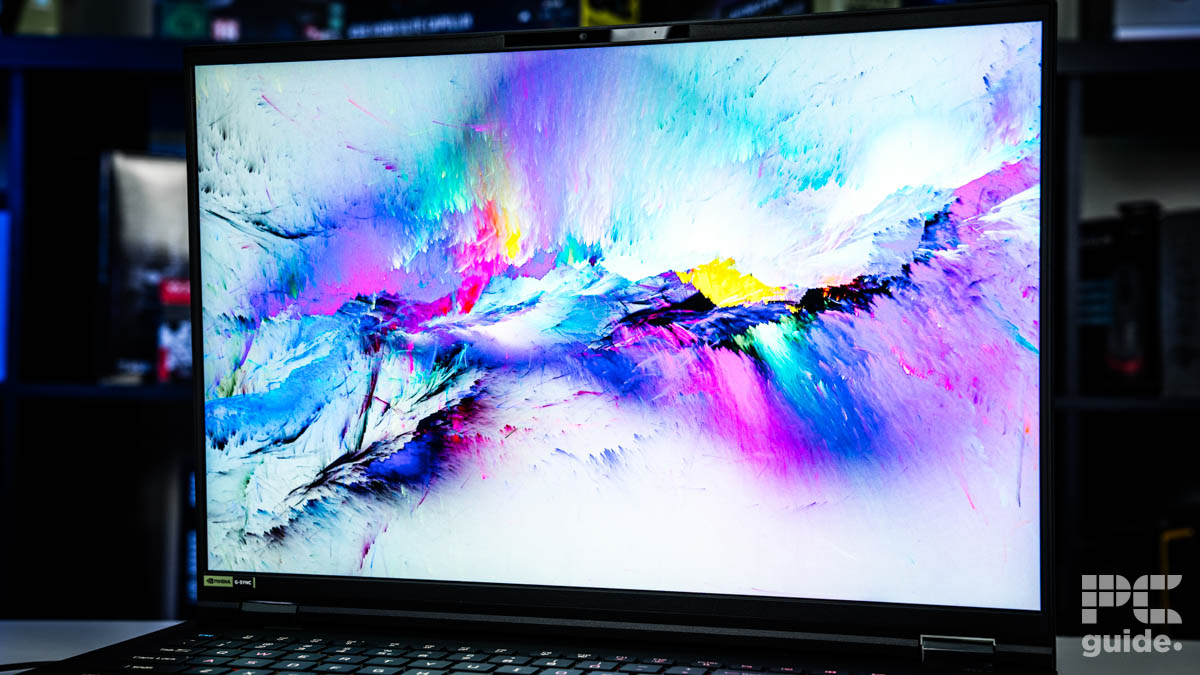 A close up of the laptop screen with a range of vibrant white mountains with colors splashed on it.