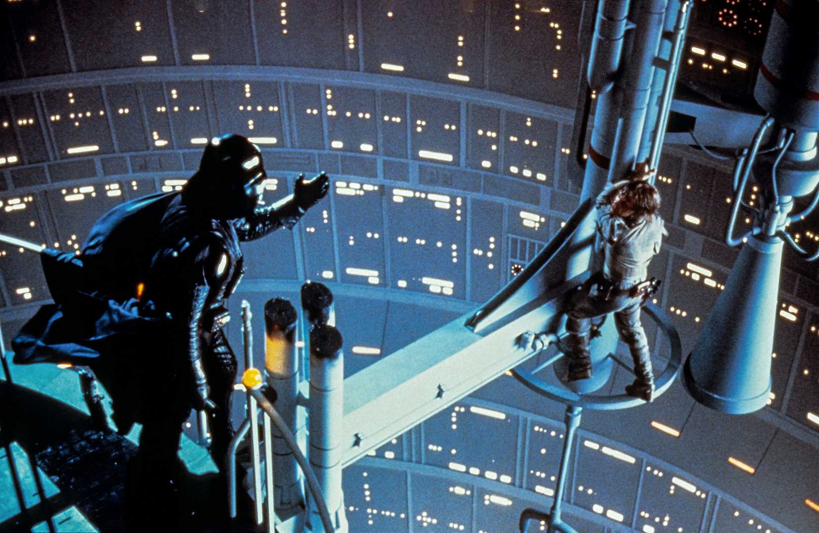 Darth Vader reaches a hand out toward Luke Skywalker (Mark Hamill), who's climbing out to the end of a gantry, in The Empire Strikes Back